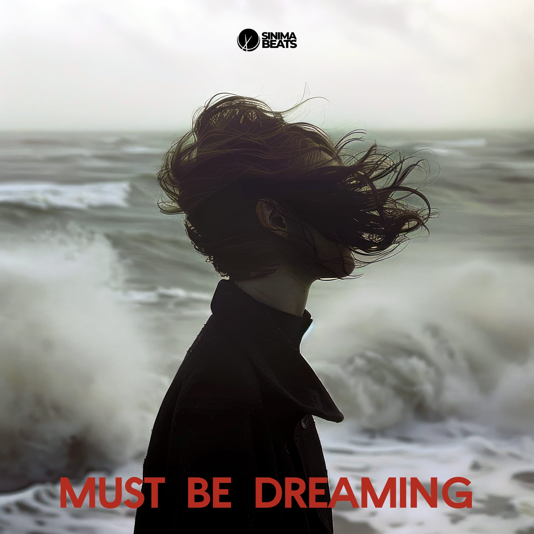 A captivating image of a woman standing on a beach, wearing a black coat with her hair blowing in the wind. The side profile view highlights her serene expression, as if lost in deep thought, evoking the feeling of being in a dream-like state. The natural elements of the wind and ocean contribute to the ethereal atmosphere, aligning with the theme, "Must Be Dreaming."