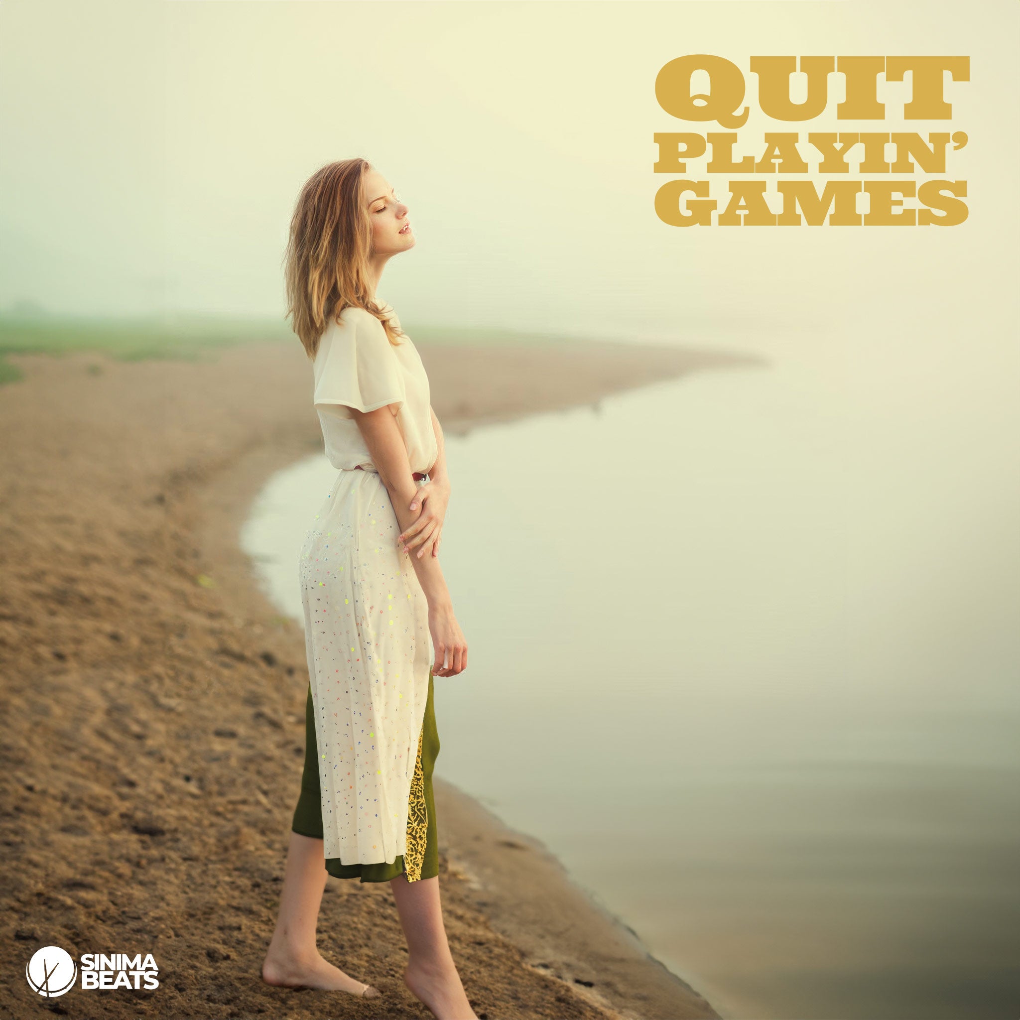 An attractive blonde woman wearing a white and jade-green dress, standing barefoot on the beach with her eyes closed, capturing a sentimental moment. This serene scene reflects the essence of ‘Quit Playin’ Games,’ emphasizing the emotional depth and tranquility of the moment.