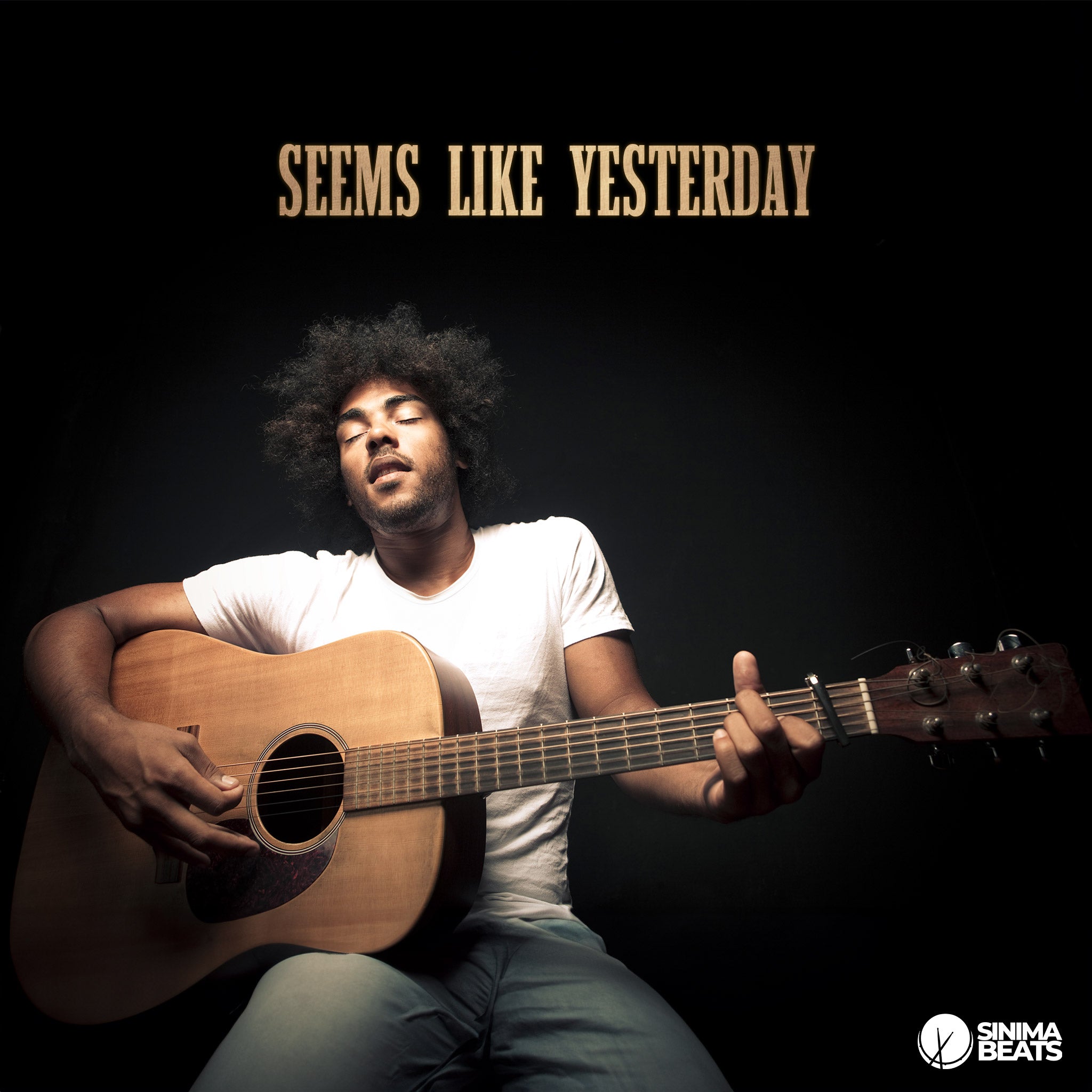 Black man with disheveled hair wearing a white t-shirt and light blue jeans, eyes closed as he passionately plays an acoustic guitar against a semi-gradient gray and black background. – Seems Like Yesterday